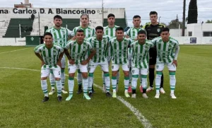 El equipo de Defensores de Vilelas posa en la cancha con su camiseta verde y blanca.