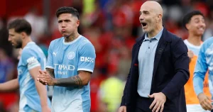 Enzo Fernández, con camiseta celeste, frente a un miembro del cuerpo técnico del Manchester City.