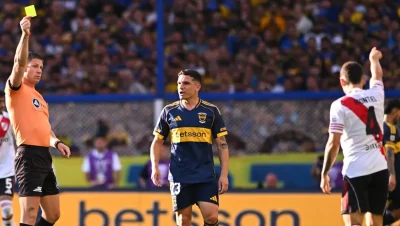 Nicolás Ramírez levanta una tarjeta amarilla durante un Superclásico entre Boca y River.