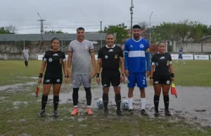 Árbitros y jugadores de Resistencia Central y Central Norte en el campo de juego embarrado.