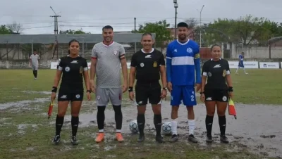 Árbitros y jugadores de Resistencia Central y Central Norte en el campo de juego embarrado.
