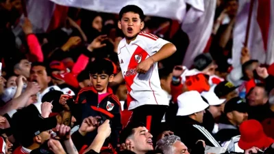 Hinchas de River celebran en la tribuna junto a un niño con la camiseta del club